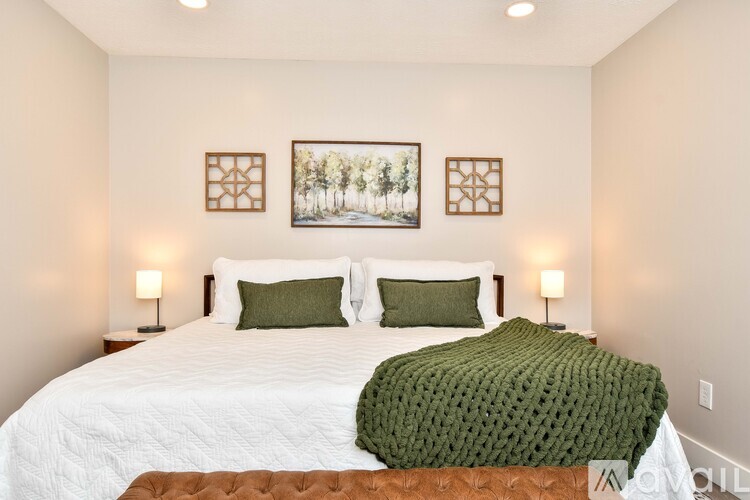 A bedroom with a large bed and two pictures on the wall.