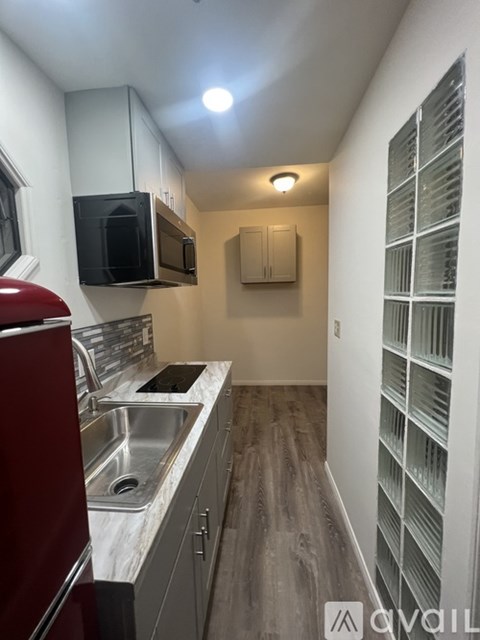 A kitchen with a red chair and a microwave above the sink.