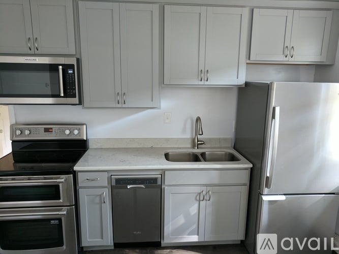 A kitchen with white cabinets and a stainless steel refrigerator.