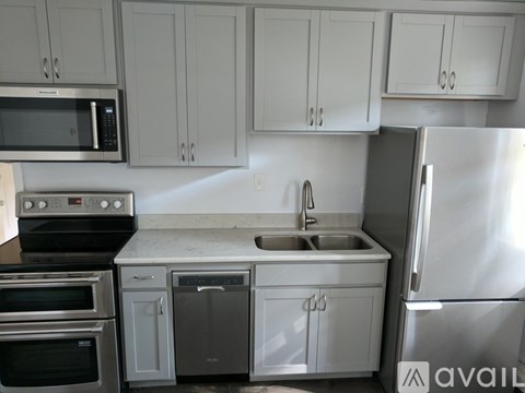 A kitchen with white cabinets and a stainless steel refrigerator.