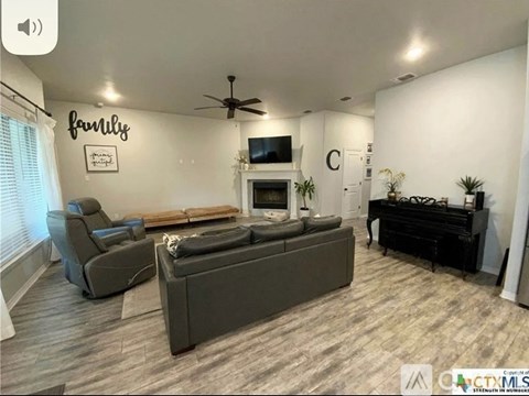 A living room with a grey sofa set, a television, and a piano.