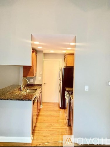 A kitchen with a granite counter top and wooden floors.