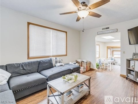 A living room with a grey couch and a ceiling fan.