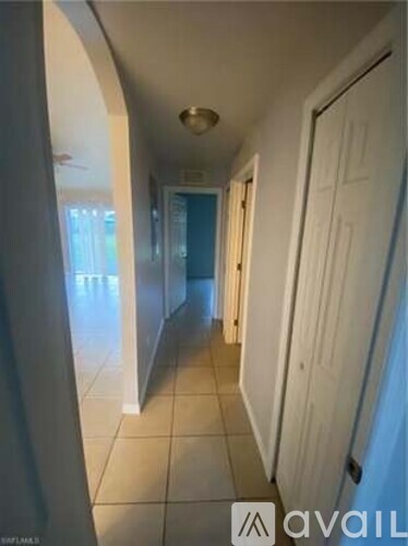 A long hallway with white doors and tiled floors.