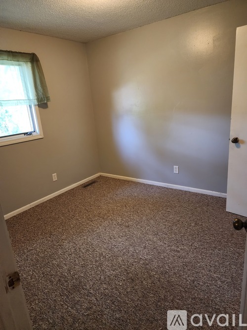 A room with carpeted floor and a door on the right.