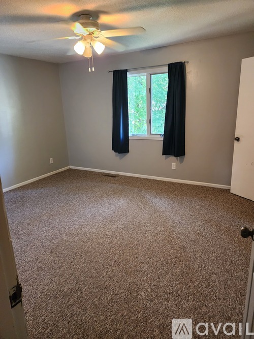 A room with a carpeted floor and a ceiling fan.