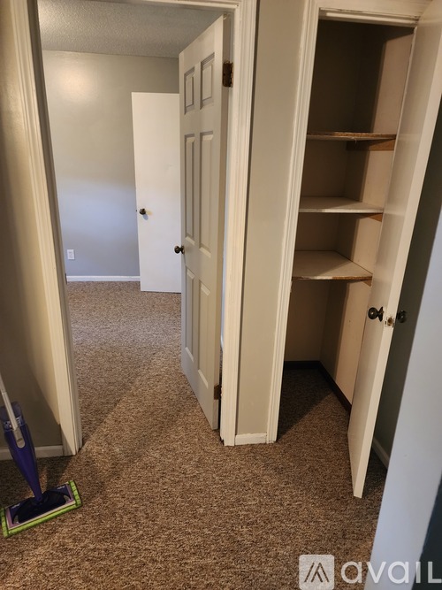 A hallway with a white door and a carpeted floor.