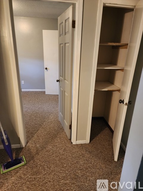 A hallway with a white door and a carpeted floor.
