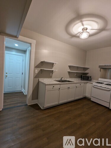 A kitchen with white cabinets and a wooden floor.
