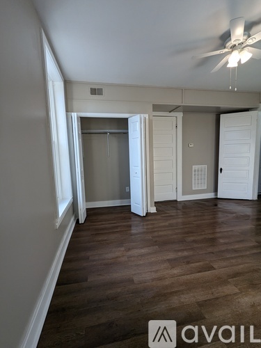 A room with a ceiling fan and wooden flooring.