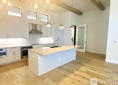 A kitchen with white cabinets and a wooden floor.