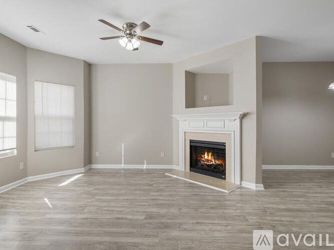 A spacious living room with a fireplace and a ceiling fan.