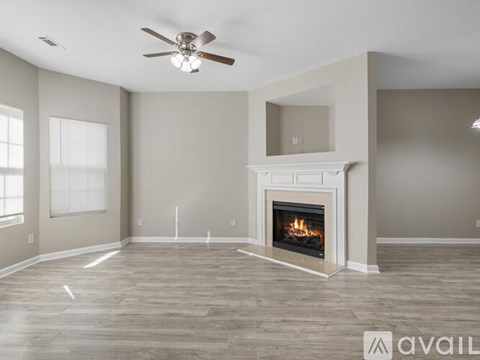 A spacious living room with a fireplace and a ceiling fan.