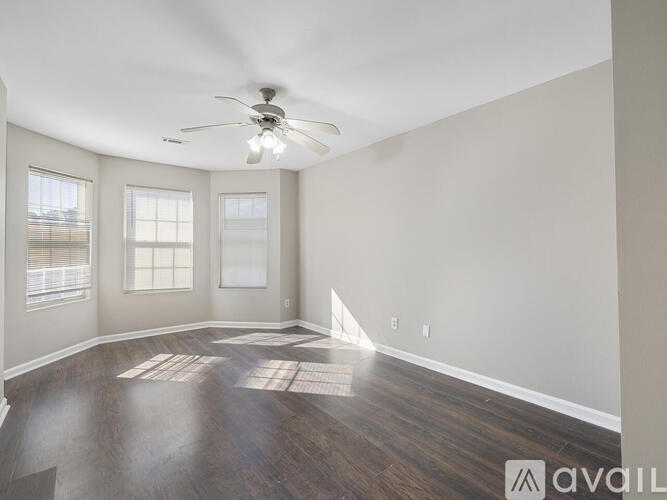 A spacious room with a ceiling fan and wooden flooring.