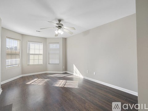 A spacious room with a ceiling fan and wooden flooring.