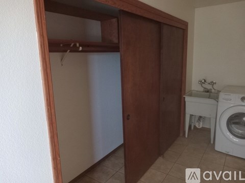 A room with a wooden wardrobe and a washing machine.