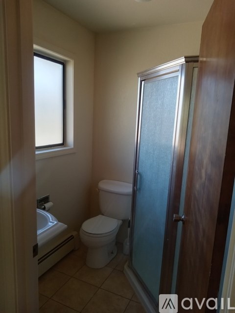 A bathroom with a toilet, sink, and shower stall.