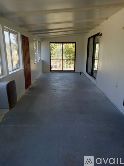 A large empty room with a slanted ceiling and a door leading outside.
