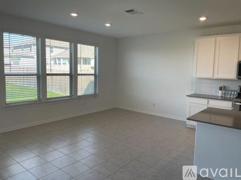 A spacious kitchen and living room with white cabinets and a large window.