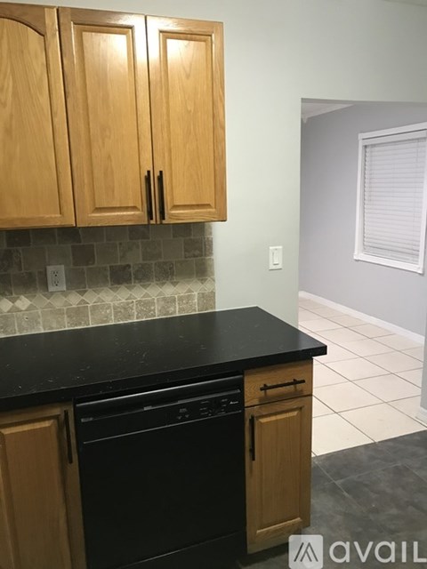 A kitchen with wooden cabinets and black countertops.