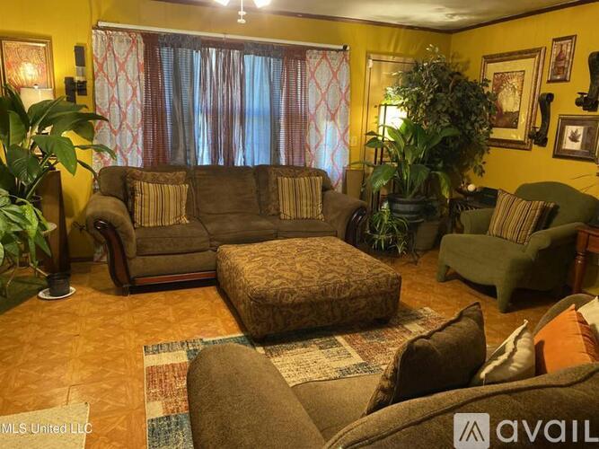 A living room with a brown couch, a green armchair, and a brown ottoman.
