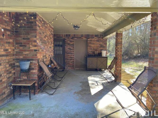 A patio with a brick wall and a table and chairs.