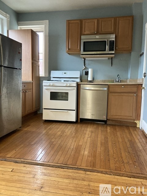 A kitchen with wooden floors and a white stove top oven.