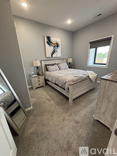 A bedroom with a large bed, nightstands, and a painting on the wall.