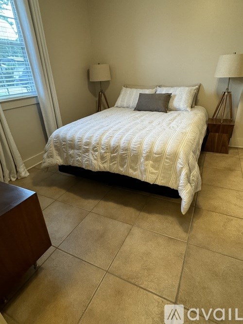 A bedroom with a bed, nightstands, and a window.