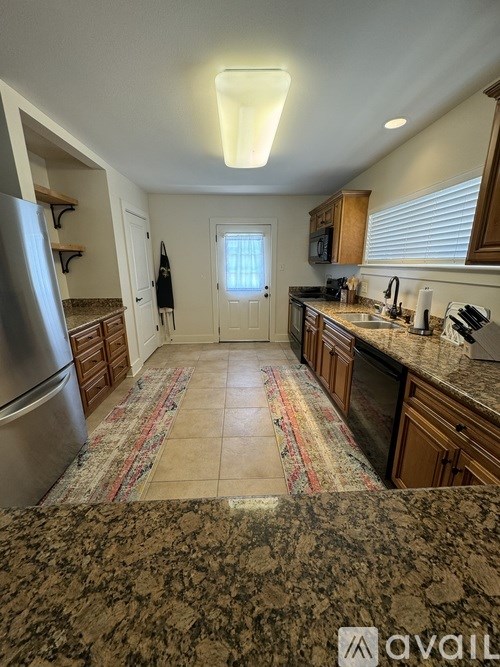 A kitchen with granite countertops and a refrigerator.