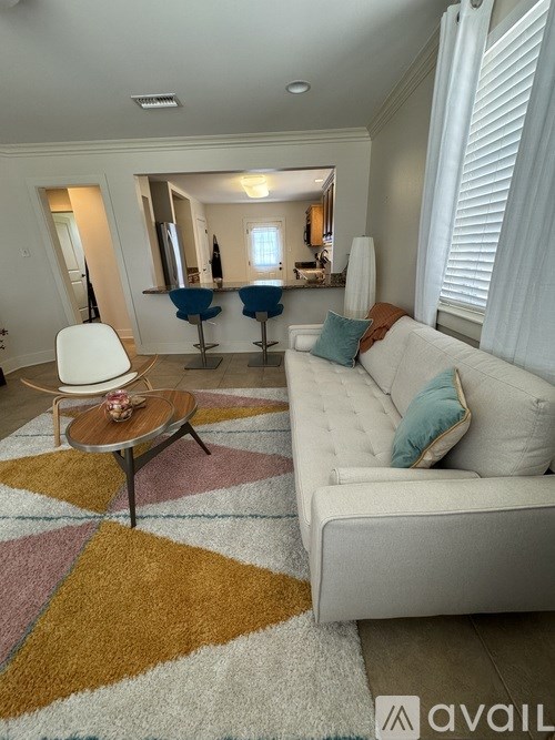 A living room with a white couch and a round table with a wooden top.