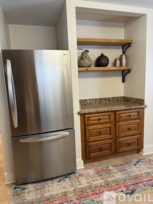 A kitchen with a stainless steel refrigerator and wooden cabinets.