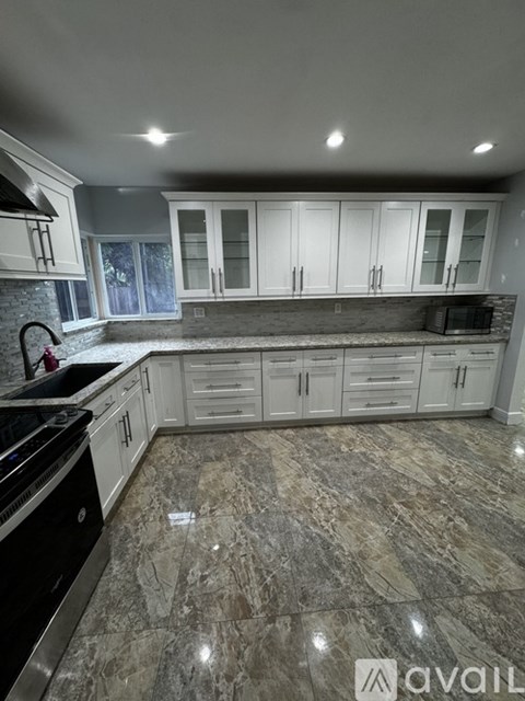 A kitchen with granite countertops and white cabinets.