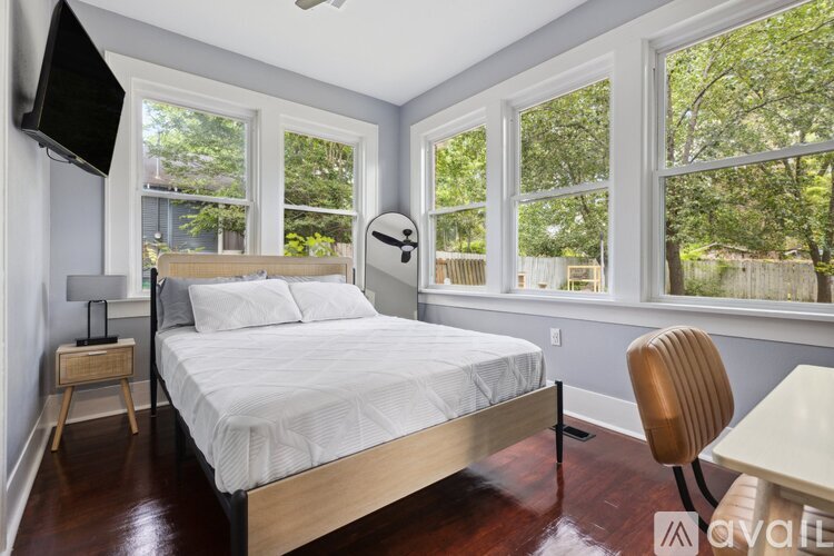 A bedroom with a bed, chair, and a window overlooking a backyard.