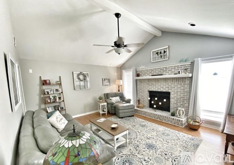 A living room with a grey couch and a fireplace.