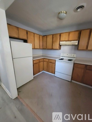 A kitchen with white appliances and wooden cabinets.