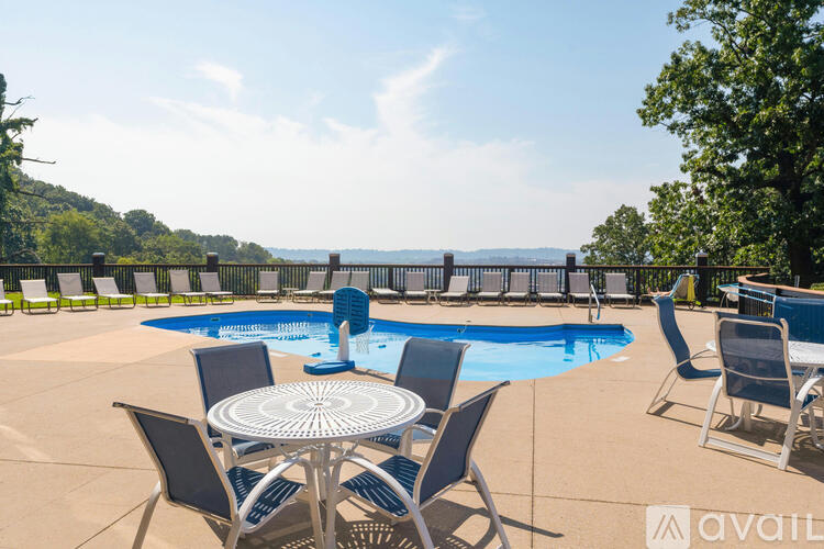 A pool area with chairs and a table with a view of the water.