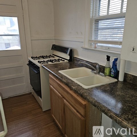 A kitchen with a stove, sink, and window.
