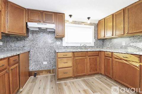 A kitchen with wooden cabinets and a marble countertop.