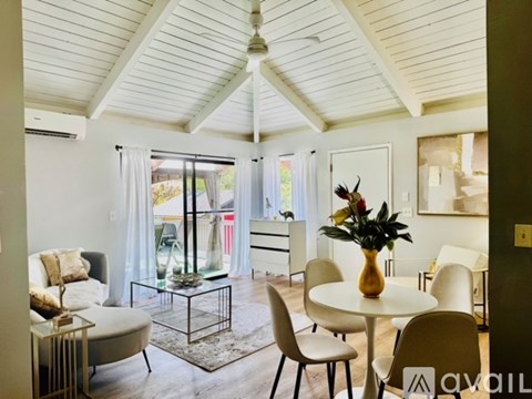 A living room with a glass table and white chairs.