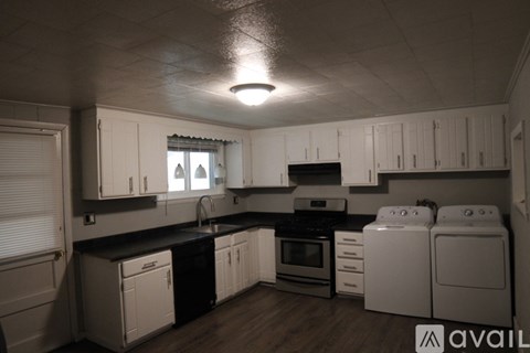 A kitchen with white cabinets and black countertops.