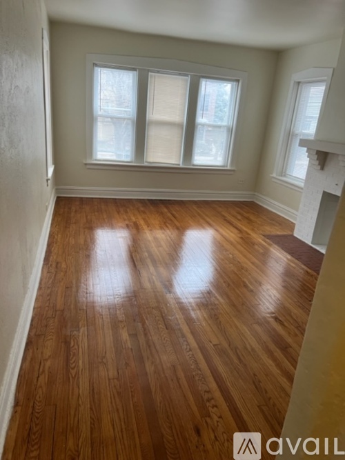 A room with wooden floors and three windows.