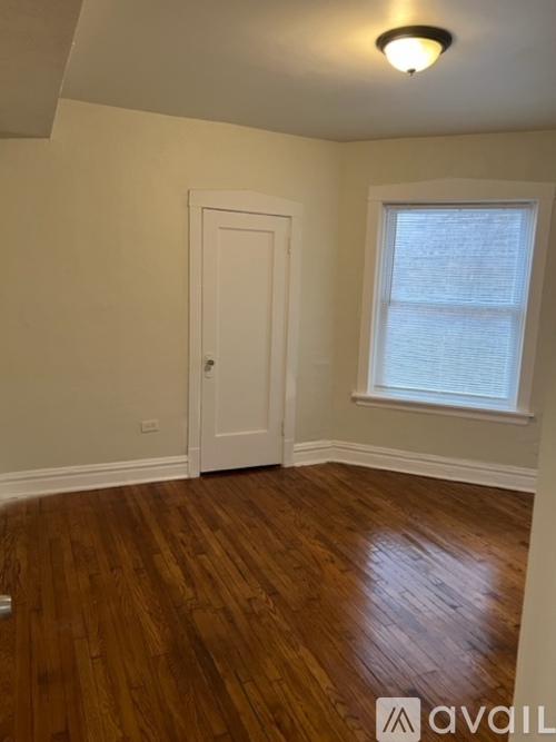 A room with a wooden floor and a window with blinds.