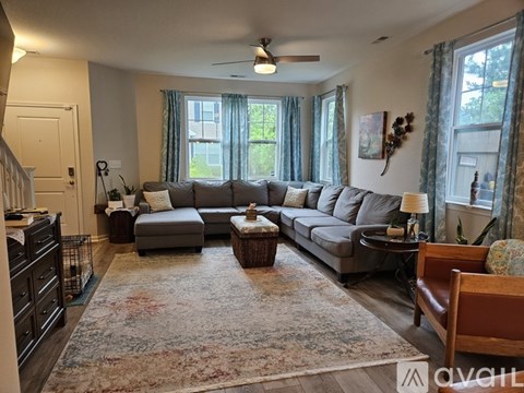 A living room with a grey couch and a rug.