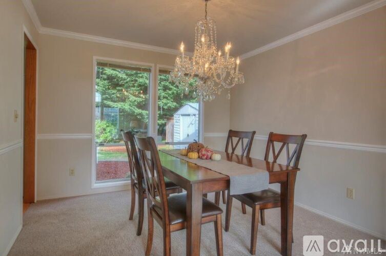 A dining room with a table set for four and a chandelier.