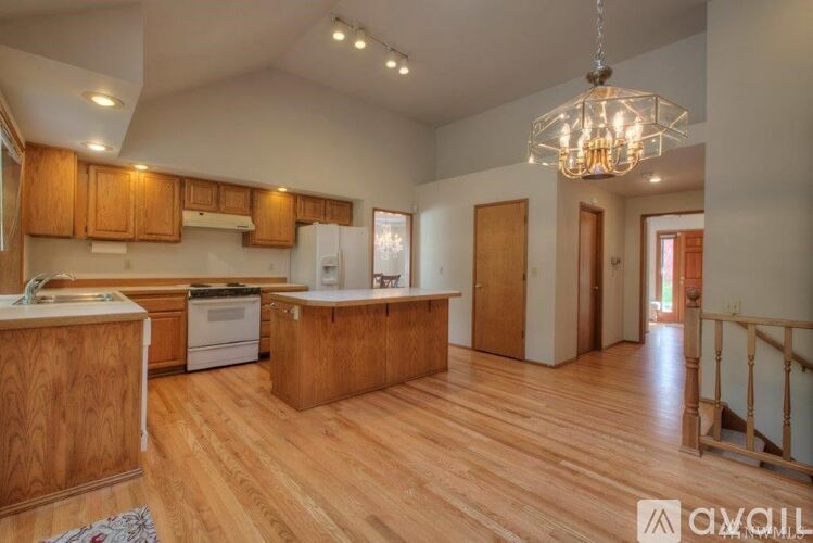 A kitchen with wooden floors and a chandelier hanging from the ceiling.