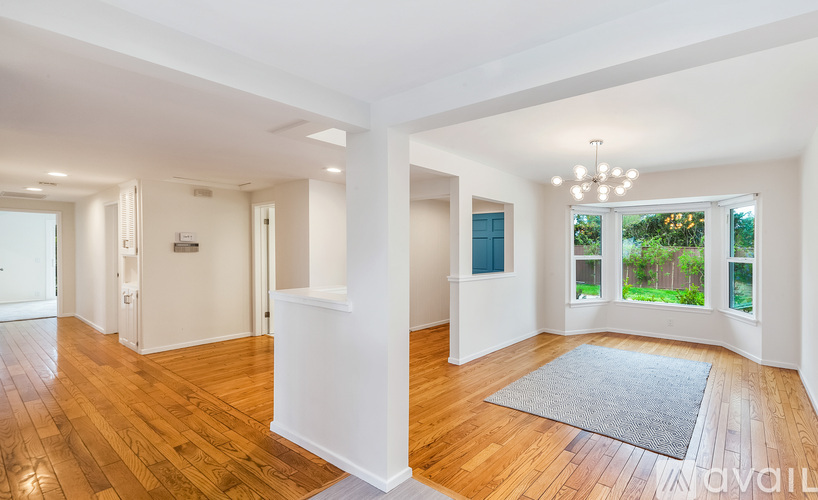 A spacious room with wooden floors and white walls.