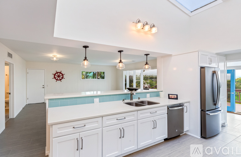 A kitchen with white cabinets and a skylight.