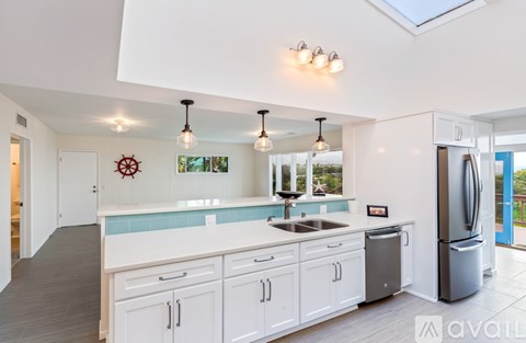 A kitchen with white cabinets and a skylight.