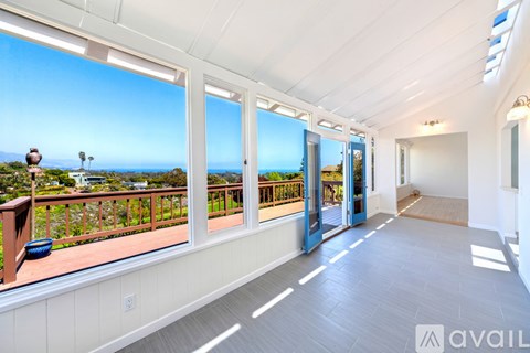 A balcony with a view of the ocean and palm trees.